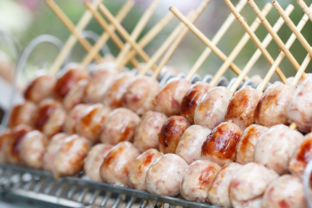 Thai street food, Sausage is grilled on a hot plate to prepare customersの写真素材