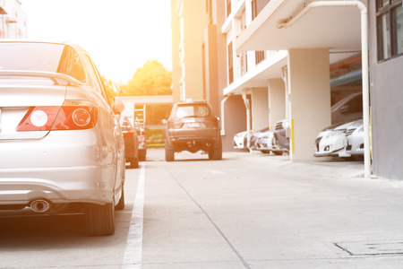 Car parked neatly inside an outdoor parking lot with car runing in back.の写真素材