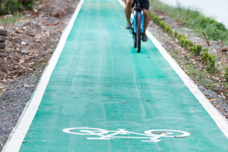 Bicycle road sign on asphalt with blurred people riding in back.