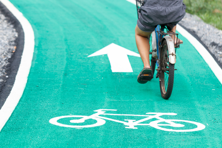 Bicycle road sign on asphalt with blured people riding in back.の写真素材