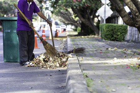 Man worker cleaning the road with green trash bin background on daytime.の写真素材