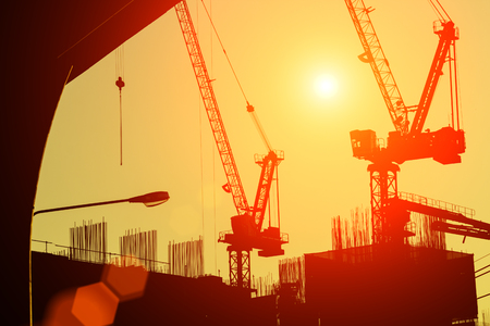 silhouette of building under construction with crane during sunset sky background.の写真素材