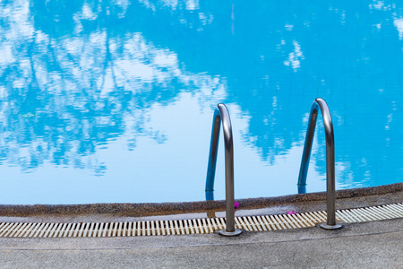 Grab bars ladder in the blue water outdoor swimming pool.の写真素材