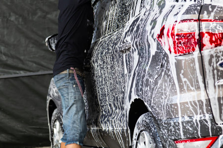 Manual car wash in car wash shop service with employee worker in back.の写真素材