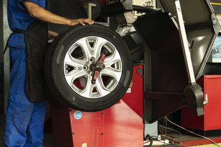 Man worker with Wheel balancing machine for car tire repair service.の写真素材