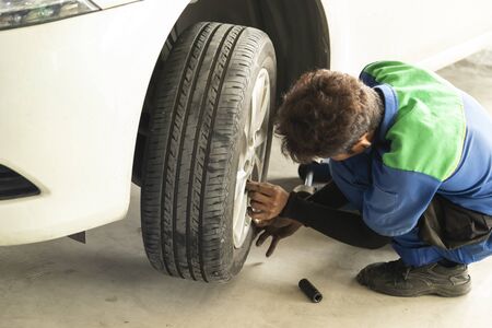 Worker working on car wheel repair at automobile repair service station.の写真素材