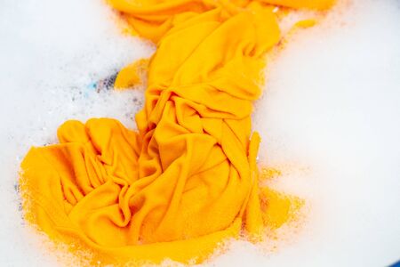 Closeup yellow color clothes washing in blue basin.の写真素材