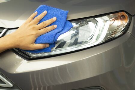 Hand of employees  worker use clean blue micro-fiber cloth to cleaning the car after washing in the car wash shop.の写真素材