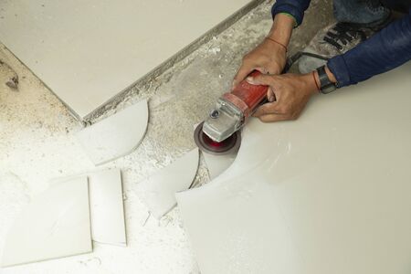 Top view of workers cut the tiles into the shape with electric tile cutter with or angle grinder to pave the floor.の写真素材