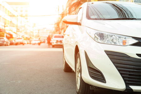 Front of white car parked neatly inside an outdoor parking lot on road.のeditorial素材