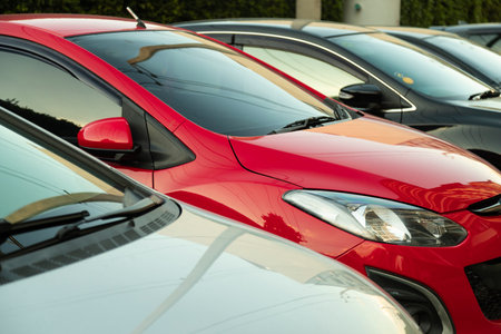 Red car parked in line neatly inside an outdoor parking lot.のeditorial素材