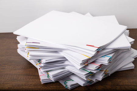 Stack of overload document paper with colorful paperclip place on wooden table, business concept...