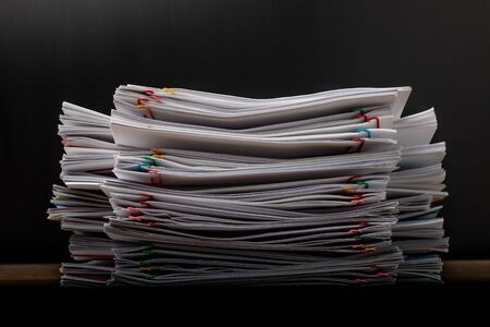 Stack of overload document paper with colorful paperclip place on wooden table, business concept footage paperless used.の写真素材