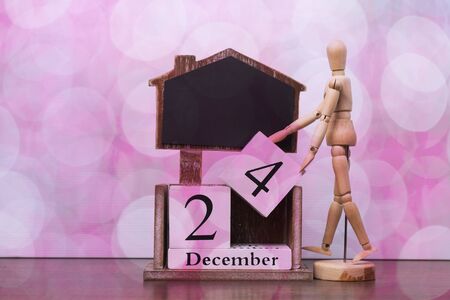 The wooden puppet is raising the number 24 december to prepare to celebrate Christmas Eve.の写真素材