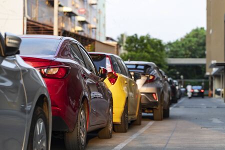 Back red and yellow cars parked in line neatly in the parking lot outside the office building on evening.の写真素材