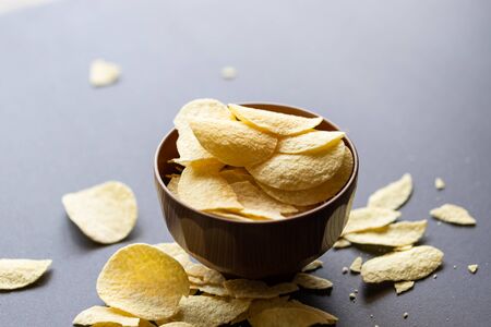 Crispy potato chips in wooden bowl on black background.の写真素材