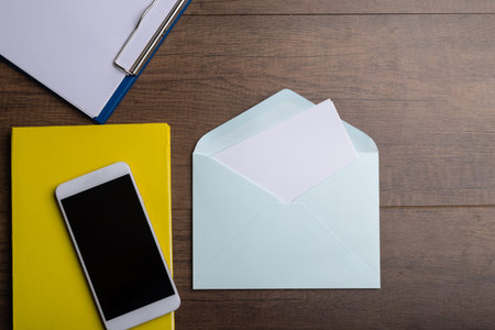 Top view open envelope and copy space with smartphone yellow diary and blank paper on clip borad.