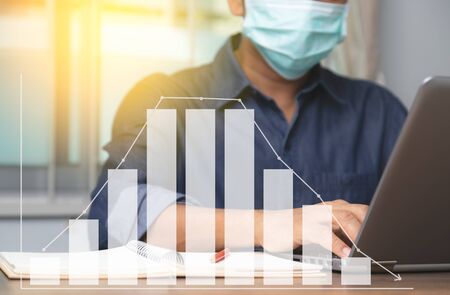 Male employee wearing a health mask and graph Preventing corona virus covid-19 infection trend, concept of working from home and social distancing.の写真素材