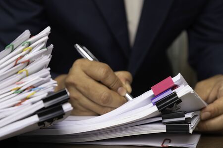 Male office workers holding and writing documents on office desk, Stack of business paper.