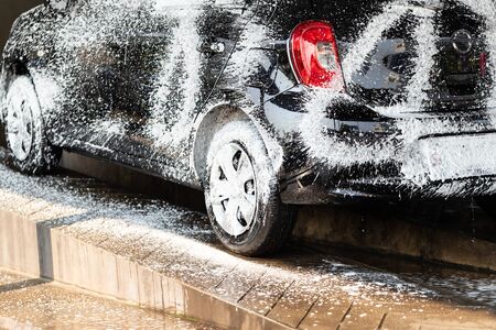 The car was sprayed with foam to wait for cleaning in the car wash shop.の写真素材