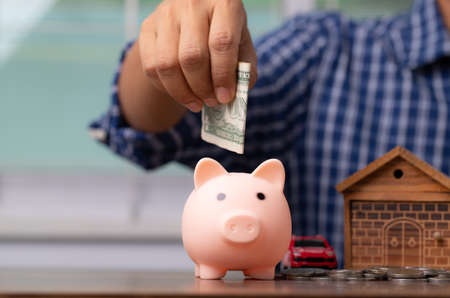 Man hand putting money into piggy for saving wealth and financial concept.の写真素材