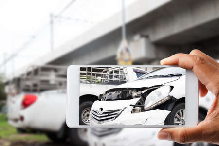 Close-up hand man holding smartphone and take photo of car accidentの写真素材