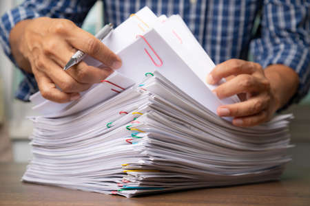 Business man hand pick up Stack overload document report paper.