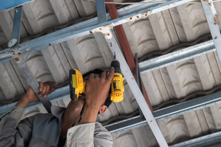 Worker hand injured using electric shovel to repair the roof, work safety concept.の写真素材