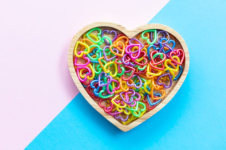 Minimalist multi-colored heart symbol shapes in wooden heart shape, Valentine's Day concept.