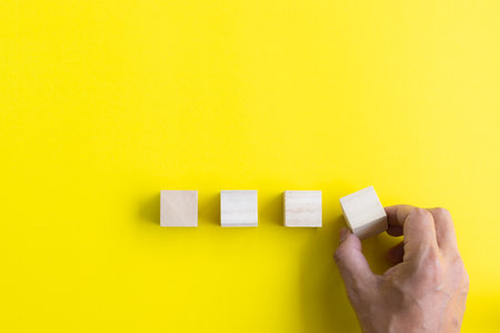 hand putting blank wooden cube on yellow background with copy space. strategy idea concept.の写真素材