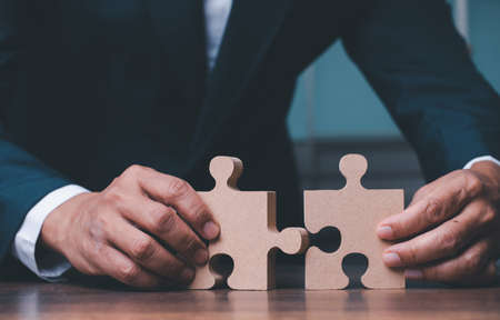 Businessman hand connecting jigsaw puzzle on desk, Business solutions, concept of success and strategy.の写真素材