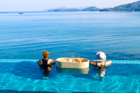 Asian woman tourists in the pool with floating breakfast for who staying on holiday, the floating brrakfast is the key tourism symbol of hotels in Phuket, Thailand.の写真素材