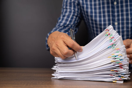 Close-up of man worker holding stack of group report papers Document clipped in color clips with...