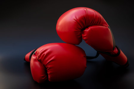 Pair of red leather boxing gloves on black background, concept of fighting and martial arts.