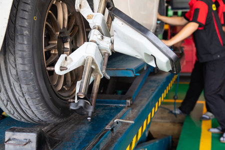 Closed up of white car wheel test in service shop with employee in back. concept of maintenance and...