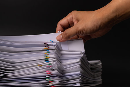 Close-up Hand holding Stack of Group report papers Document clipped in color clips, business, and education concept.の写真素材