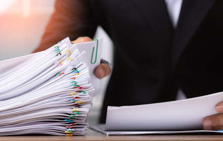 Business man or office workers holding documents for writing on office desk, Stack of business overload paper.の写真素材