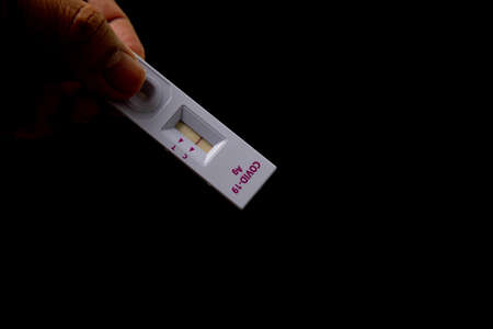Hand holding Rapid kits of Covid-19 Ag test or ATK seen on black background with copy space, concept for control of corona virus 2019 epidemic.の写真素材