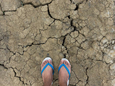 Feet in sandals on cracked ground, poverty and drought concept.の写真素材