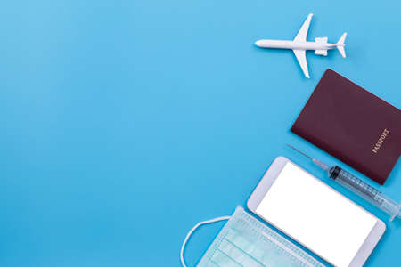Flat lay of airplane, passport, health mask,  syringe for using app vaccinated person using digital health passport for travel during covid-19 pandemic.の写真素材