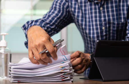 Employees wearing masks to prevent Corona virus with Document paper report , recording data on Tablet, selective focusの写真素材