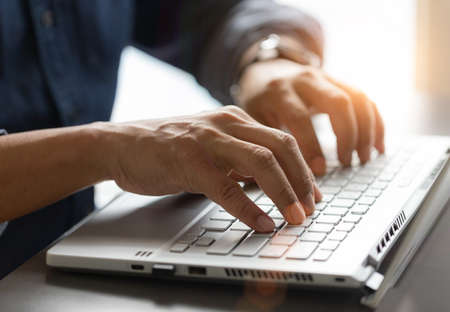 Man hand working on the laptop in office with the fair light shines through.の写真素材