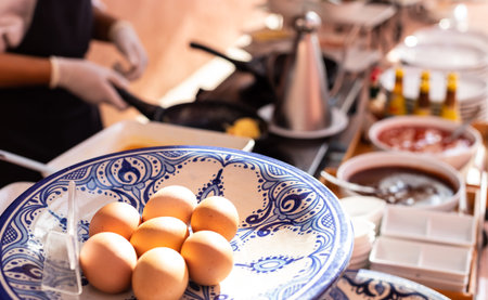 Close-up Prepared eggs make omelettes for breakfast with blurry chef cooking in the back.