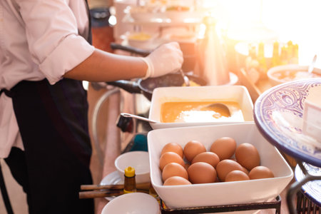 Close-up Prepared eggs make omelettes for breakfast with chef cooking in the background.