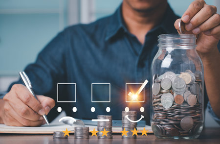 Hand of businessman holding coins putting in glass and documentation in account book. concept saving...