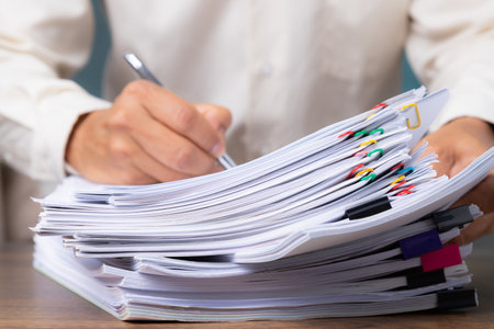 Business man hand pick up Stack overload document report paper with colorful paperclip, business and paperless concept.の写真素材