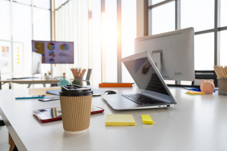 Paper coffee cup is placed on an employee's desk in the office.の写真素材