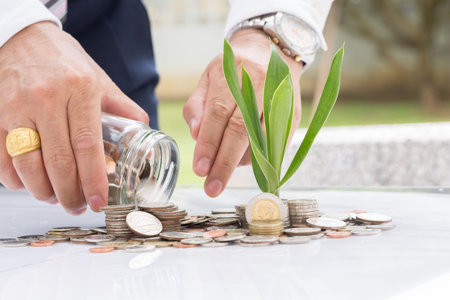 Hand putting mix coins and seed in clear bottle on white background,Business investment growth...