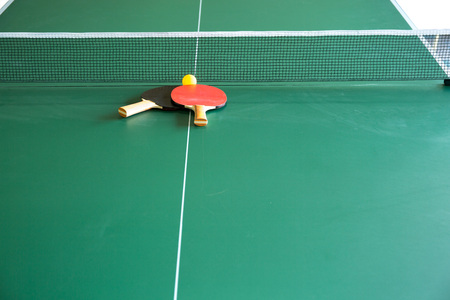 Two table tennis  rackets and balls on a green table with net; shallow DOF, focus on racketsの写真素材