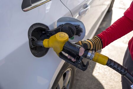 Closeup of woman pumping gasoline fuel in car at gas station. Petrol or gasoline being pumped into a motor vehicle car.の写真素材